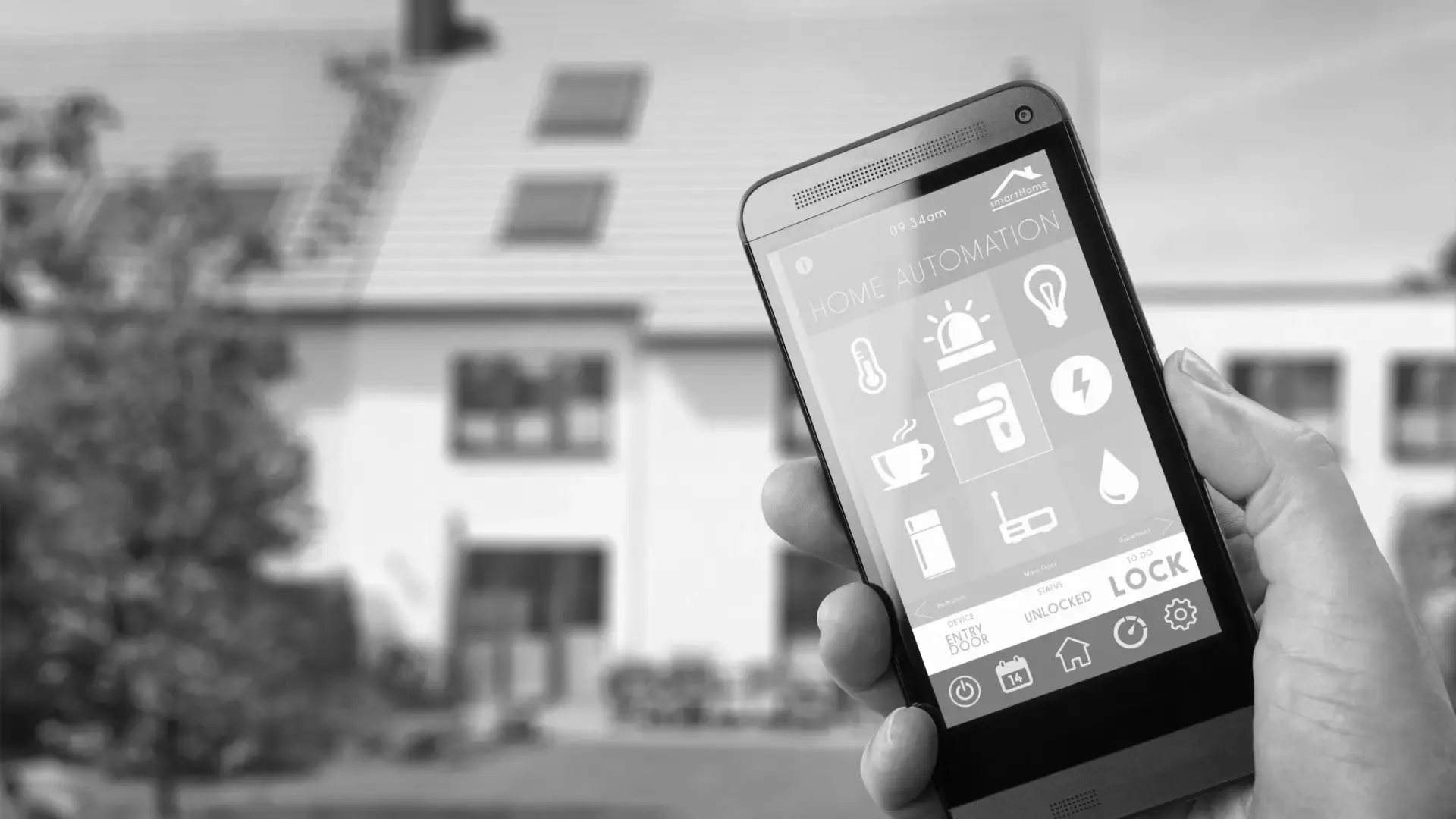 Hand holding a phone running a smart lighting control app in front of a house