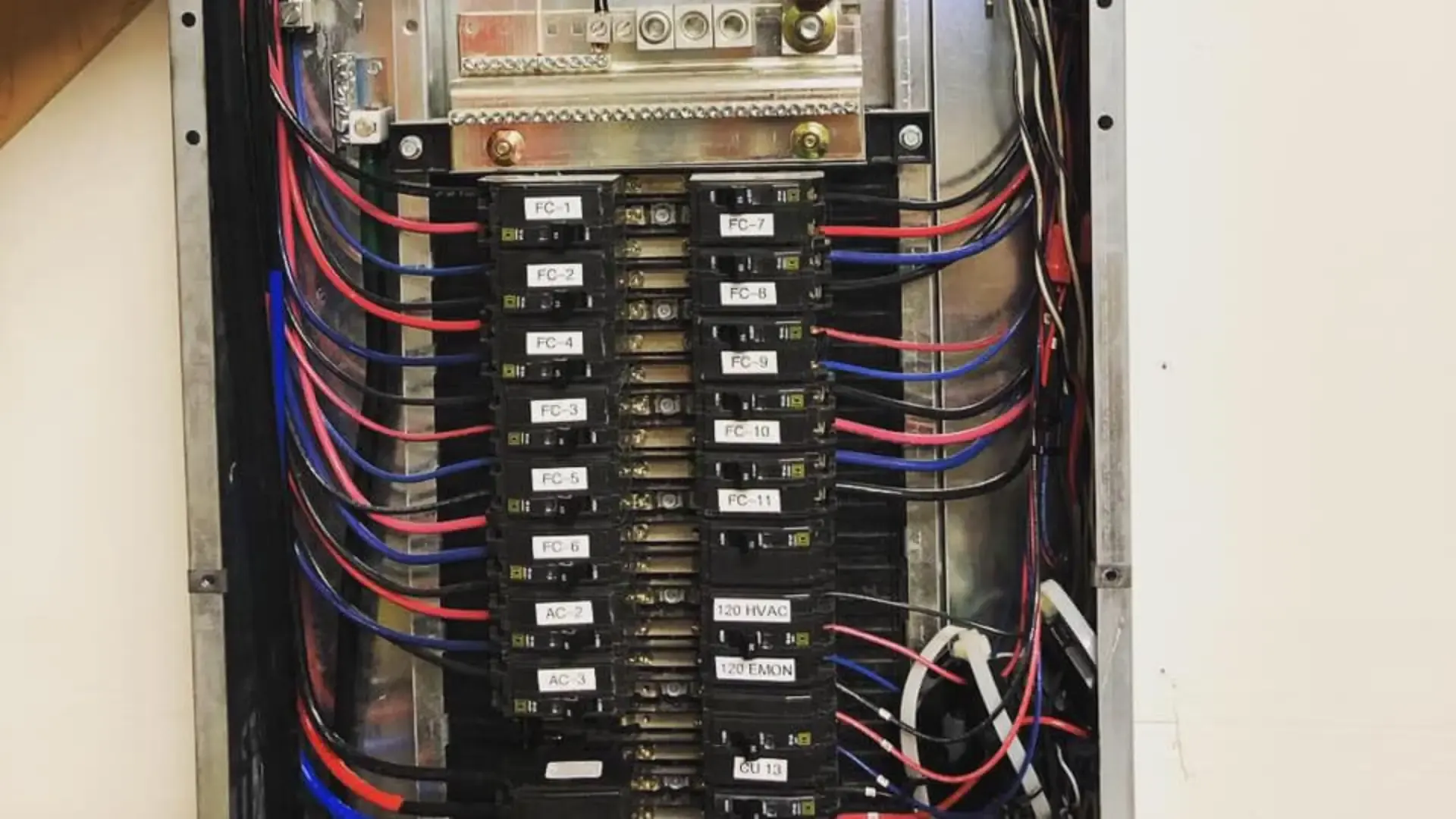 Upgraded electrical panel with breakers and colour-coded wiring behind an open cover